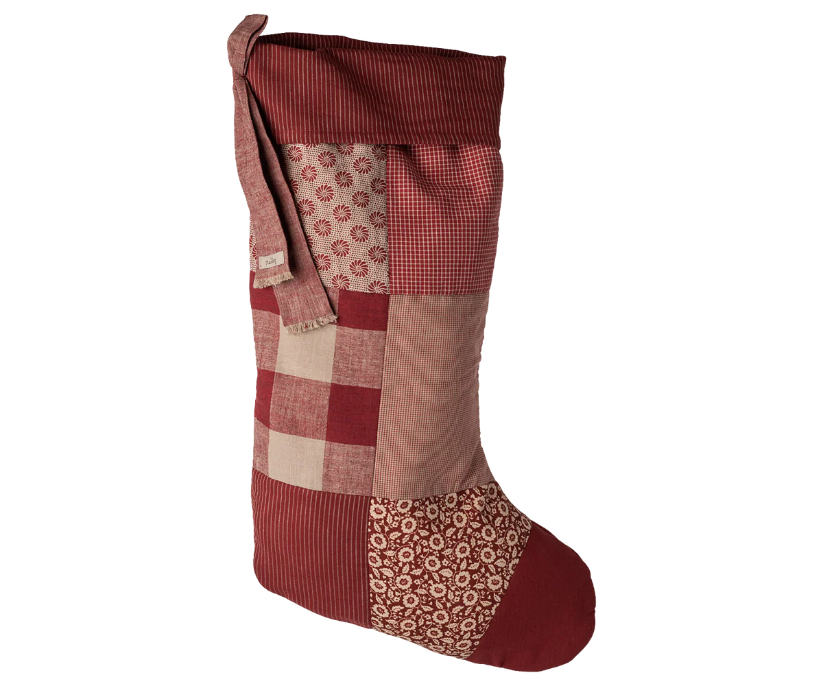 Patchwork Christmas stocking with red, brown, and beige patterns on a white background