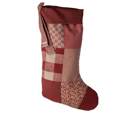 Patchwork Christmas stocking with red, brown, and beige patterns on a white background