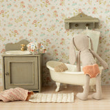 Miniature bathroom set with bathtub, sink, and toy rabbit against a floral wallpaper background | Maileg UK
