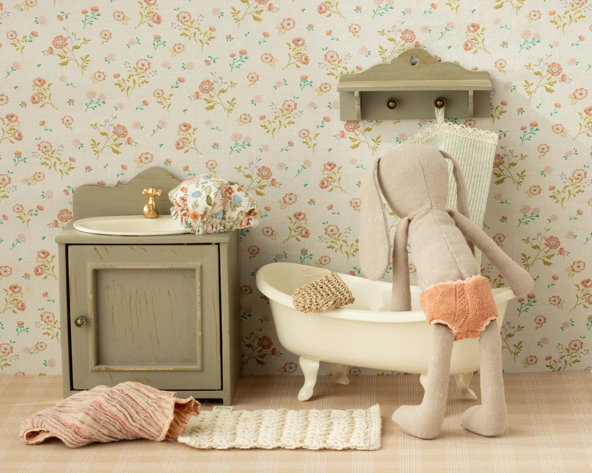 Miniature bathroom set with bathtub, sink, and toy rabbit against a floral wallpaper background | Maileg UK