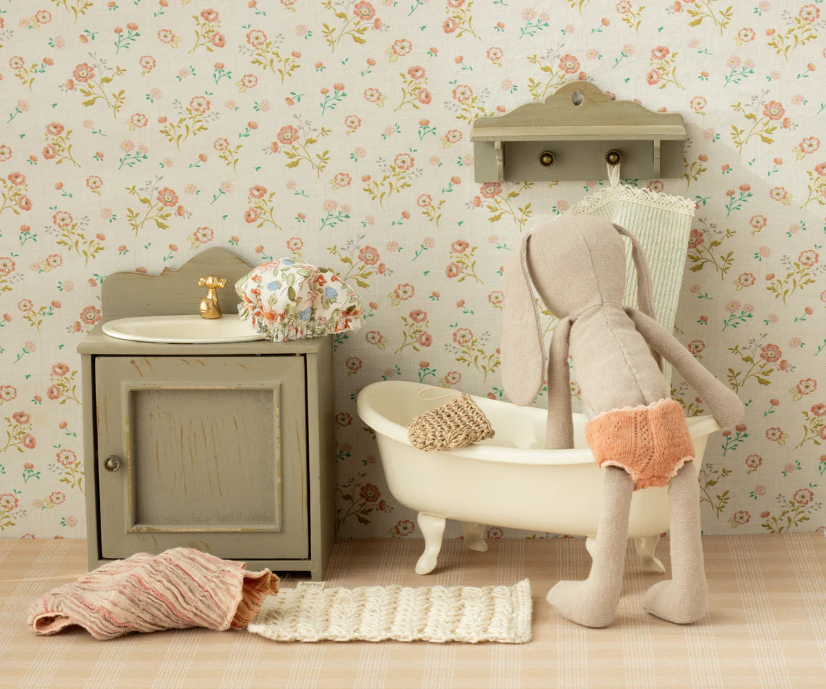 Miniature bathroom set with bathtub, sink, and toy rabbit against a floral wallpaper background | Maileg UK