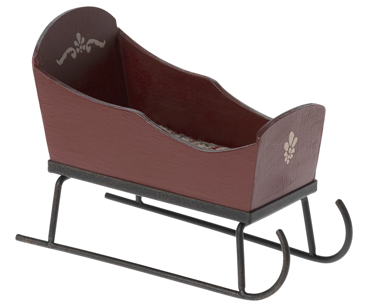 Brown wooden sleigh with black metal runners on a white background