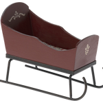 Brown wooden sleigh with black metal runners on a white background