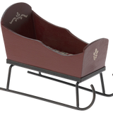 Brown wooden sleigh with black metal runners on a white background