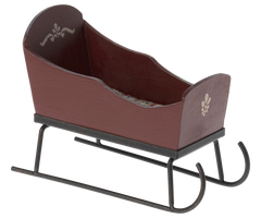 Brown wooden sleigh with black metal runners on a white background