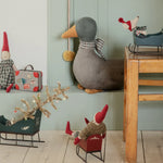 Decorative items including a duck, small figures, and sleds on a wooden floor against a light green wall. | Maileg uk