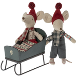 Two toy mice in festive attire with a miniature sleigh on a white background