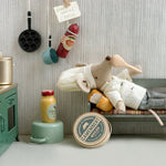 Toy chef mouse lying on a small bed in a miniature kitchen setting with various kitchen items around. |Chef clothes, Big sister and big brother mouse | Maileg UK