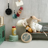 Toy chef mouse lying on a small bed in a miniature kitchen setting with various kitchen items around. |Chef clothes, Big sister and big brother mouse | Maileg UK