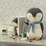 Plush penguin with a scarf on a table with a vintage radio and other items. | Maileg UK