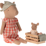 Two plush pig toys, one in a red checkered dress and floral hat, the other in a striped outfit sitting in a wooden crate. | Maileg UK