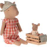 Two plush pig toys, one in a red checkered dress and floral hat, the other in a striped outfit sitting in a wooden crate. | Maileg UK