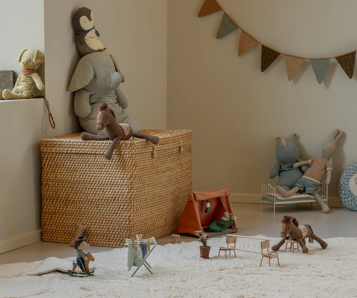 Children's toys and playset in a room with a woven basket and decorative elements.