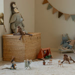 Children's toys and playset in a room with a woven basket and decorative elements.