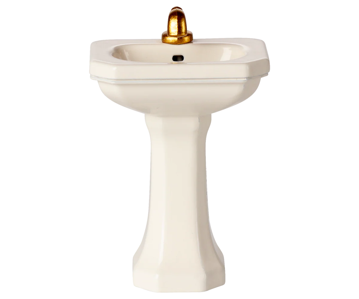 White pedestal sink with a gold faucet on a white background | Maileg uk