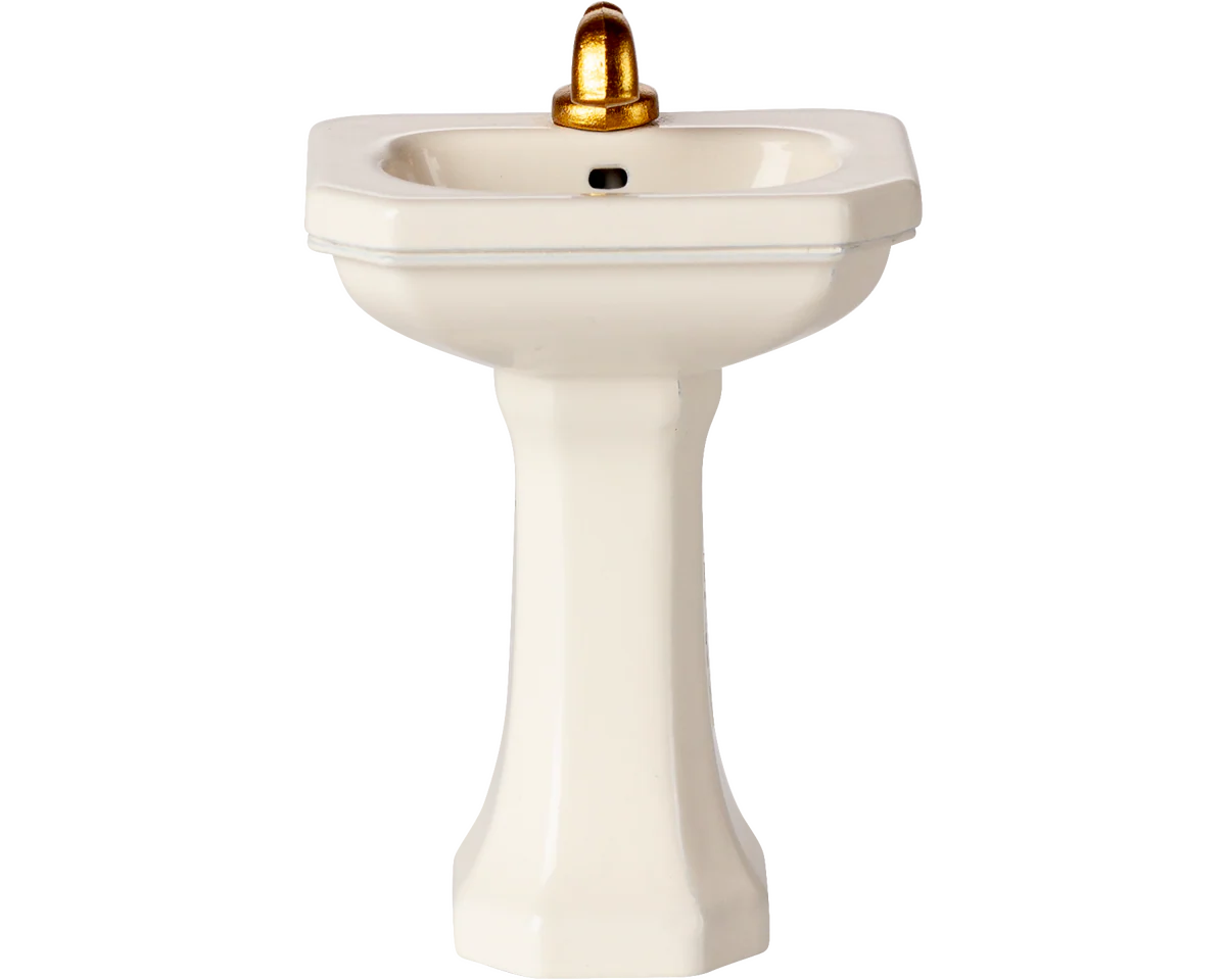 White pedestal sink with a gold faucet on a white background | Maileg uk