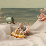 Two toy mice with beach accessories on a sandy surface with a scenic background. | Maileg UK