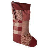Patchwork Christmas stocking with red, brown, and beige patterns on a white background