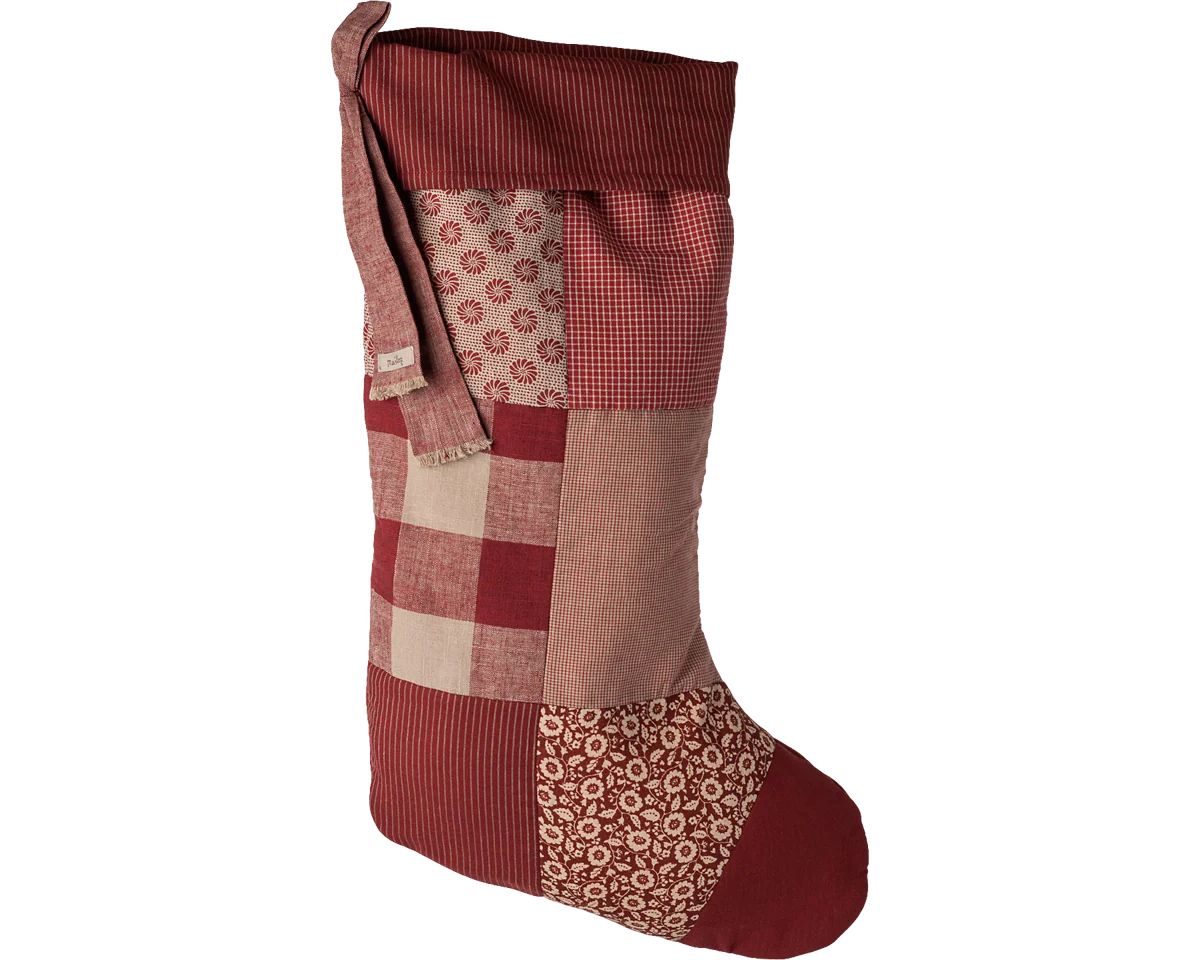 Patchwork Christmas stocking with red, brown, and beige patterns on a white background