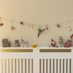 Decorative items on a white console table against a beige wall with a string of small ornaments. | Christmas Maileg UK