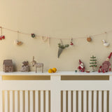 Decorative items on a white console table against a beige wall with a string of small ornaments. | Christmas Maileg UK