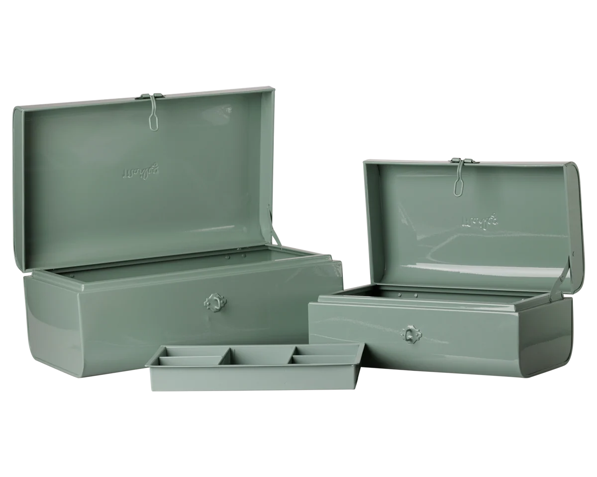 A set of two Maileg sage green metal storage boxes with hinged lids and small silver knobs, shown open with a matching tray in front, on a plain white background.
