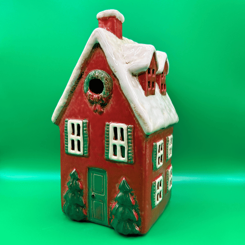 Tall red ceramic tea light candle house, snowy roof with dormer windows, christmas trees at door and a wreath. | Christmas Decor