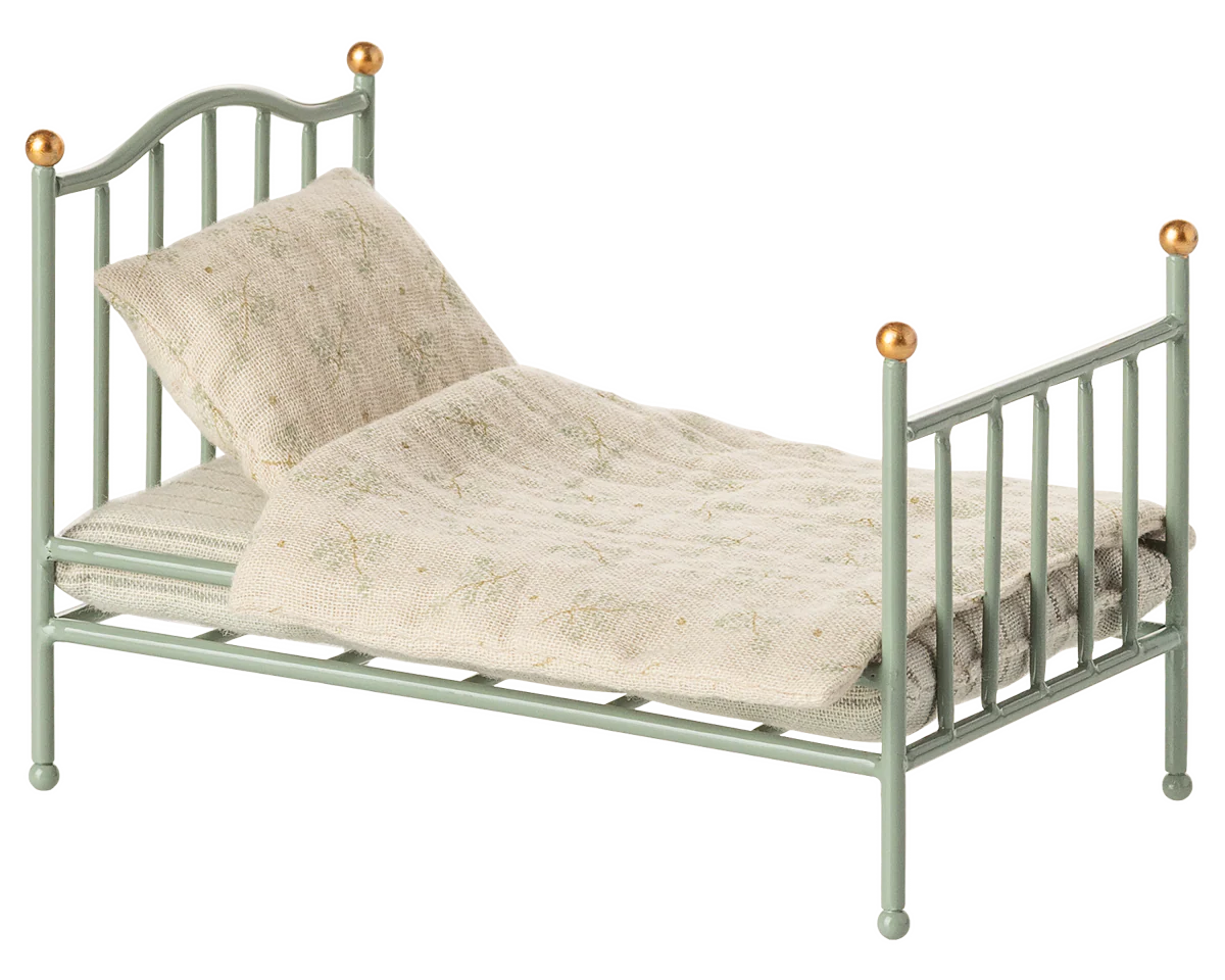 Small green metal bed with beige bedding on a white background | Maileg UK