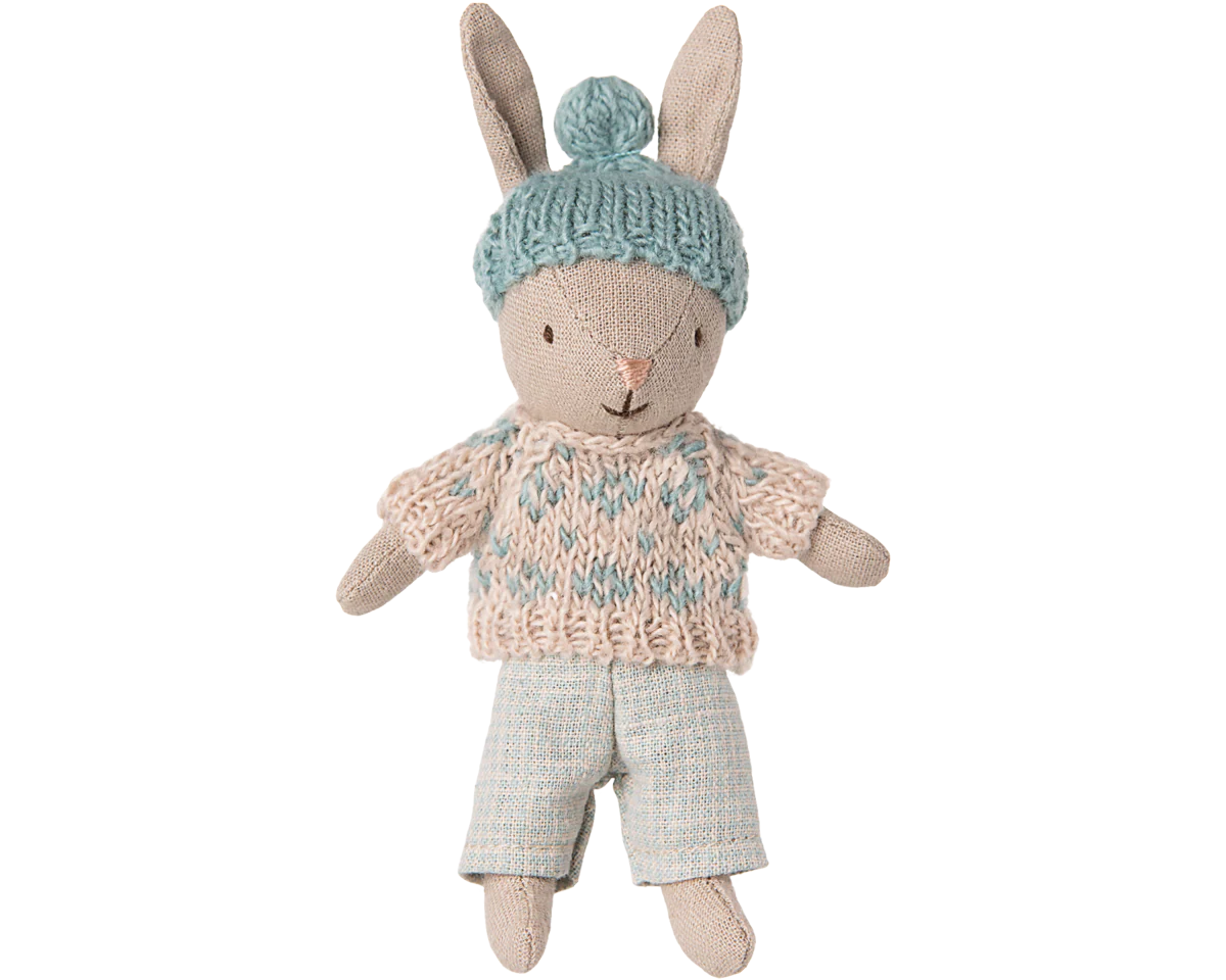 Toy rabbit wearing a knitted sweater and hat on a white background