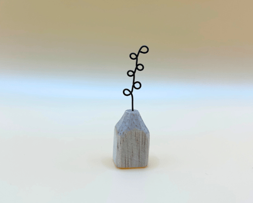 Small wooden vase with a black wire plant on a gradient background