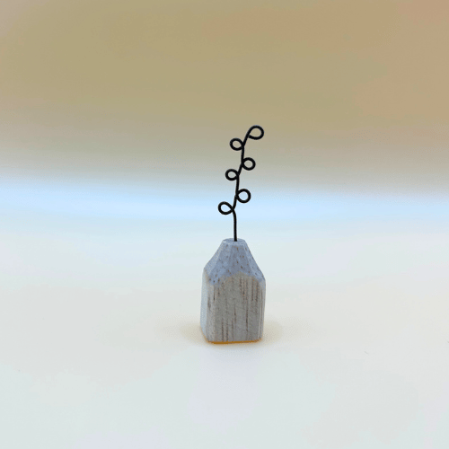 Small wooden vase with a black wire plant on a gradient background
