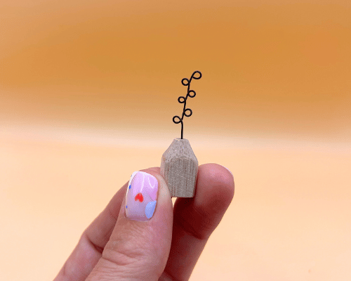 Small wooden vase with a plant on a blurred orange background