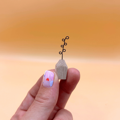 Small wooden vase with a plant on a blurred orange background