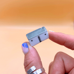 Small rectangular porcelain cottage held between fingers against a blurred background