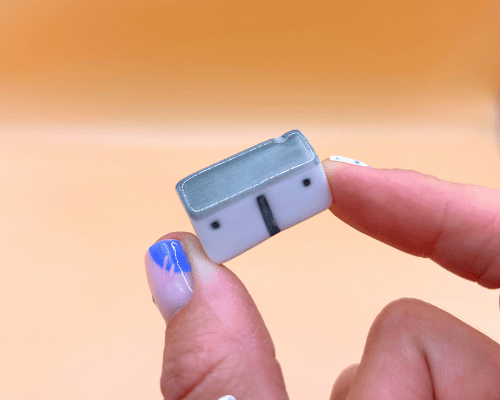 Small rectangular porcelain cottage held between fingers against a blurred background
