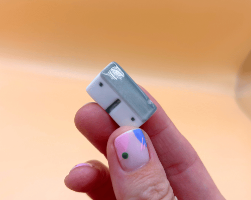 Small porcelain model cottage held between fingers against a blurred background