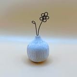 Small textured ceramic vase with a wire flower on a light background