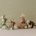 The Maileg mice are going on an adventure, 3 mice on the green tricycle and trailer while mummy mouse sits in the coral car that daddy mouse is pushing.