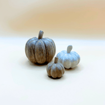 Three decorative pumpkins on a white surface with a blurred background
