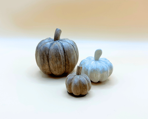 Three decorative pumpkins on a white surface with a blurred background